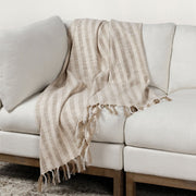 Linna 50x70 inch ivory and natural throw blanket by Classic Home, soft woven fabric displayed on a cozy sofa.