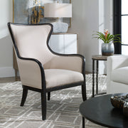 Uttermost Sandy wing back armchair in beige and dark brown fabric with plush cushioning and wooden legs.