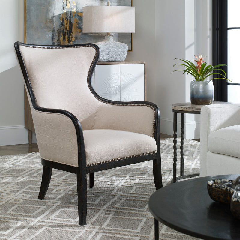 Uttermost Sandy wing back armchair in beige and dark brown fabric with plush cushioning and wooden legs.