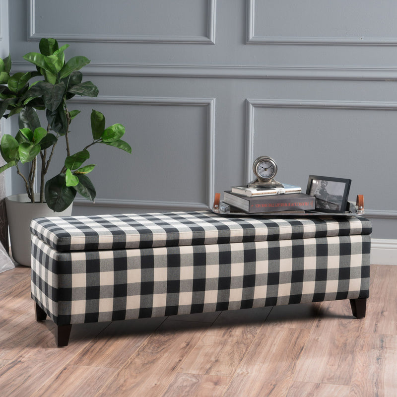 Black Noble House storage ottoman with cushioned top and interior storage, serving as seating and a functional living room accent.