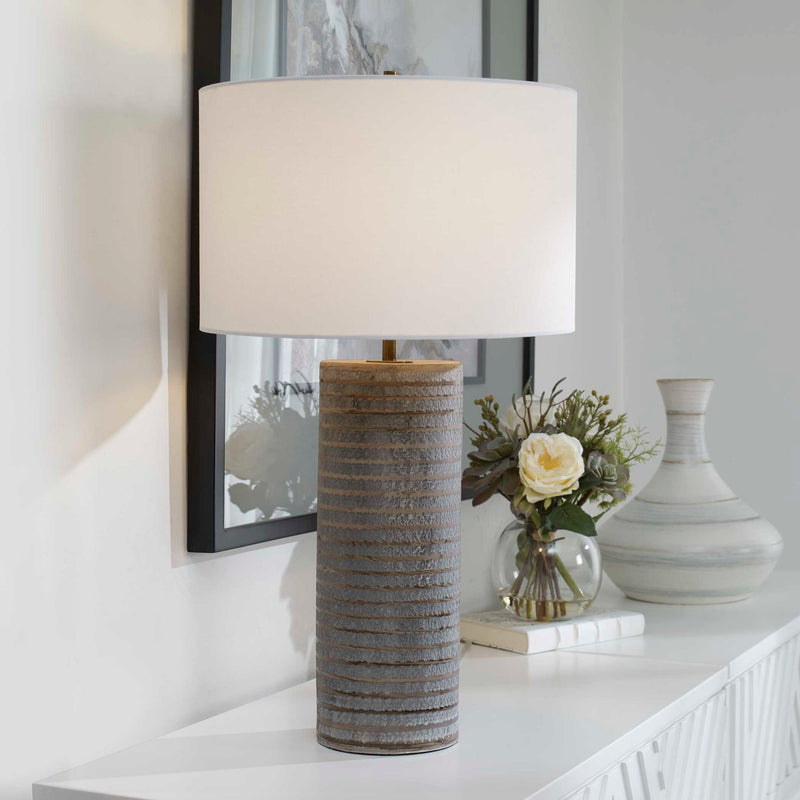 Gray Monolith table lamp by Uttermost featuring a sleek, modern design with a cylindrical base and a fabric lampshade.