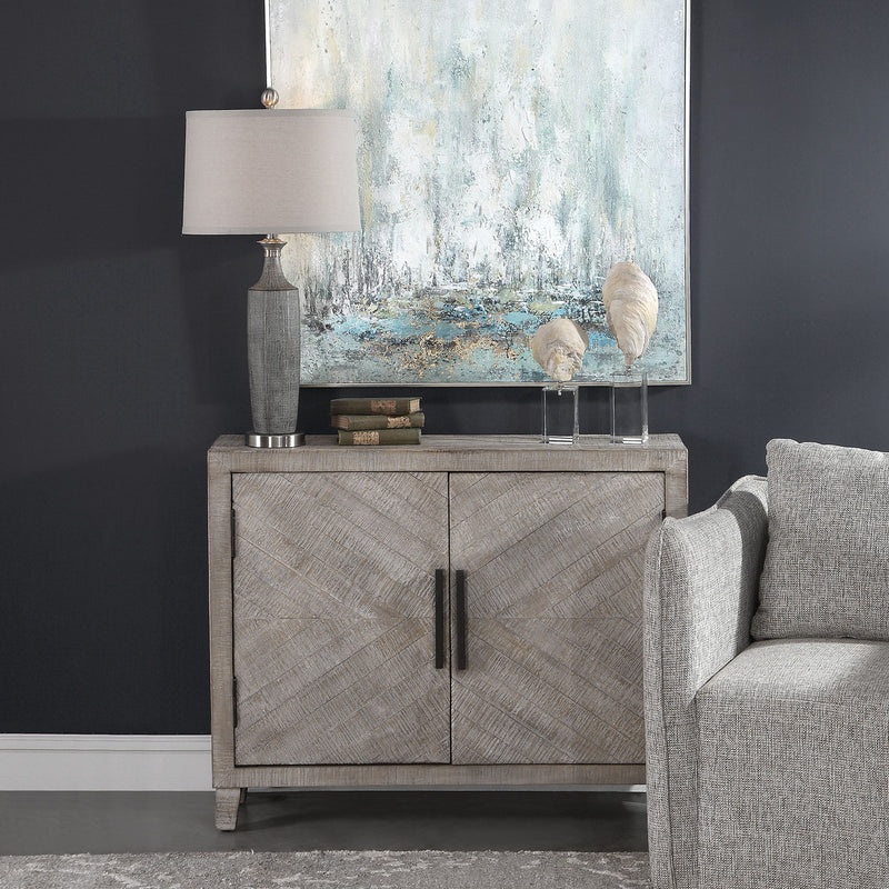 White washed Adalind accent cabinet by Uttermost featuring two doors with black hardware and a distressed finish.