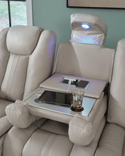 Signature Design by Ashley Elevate Edges reclining sofa with drop-down table in coin fabric, featuring plush cushions and armrests.