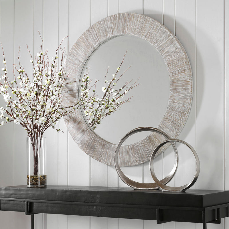 Uttermost Repose round wall mirror with whitewash finish, decorative frame, hanging on a wall with natural light.