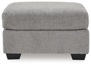 Benchcraft® upholstered Ottoman with plush fabric and tufted top, perfect for living room or bedroom decor.