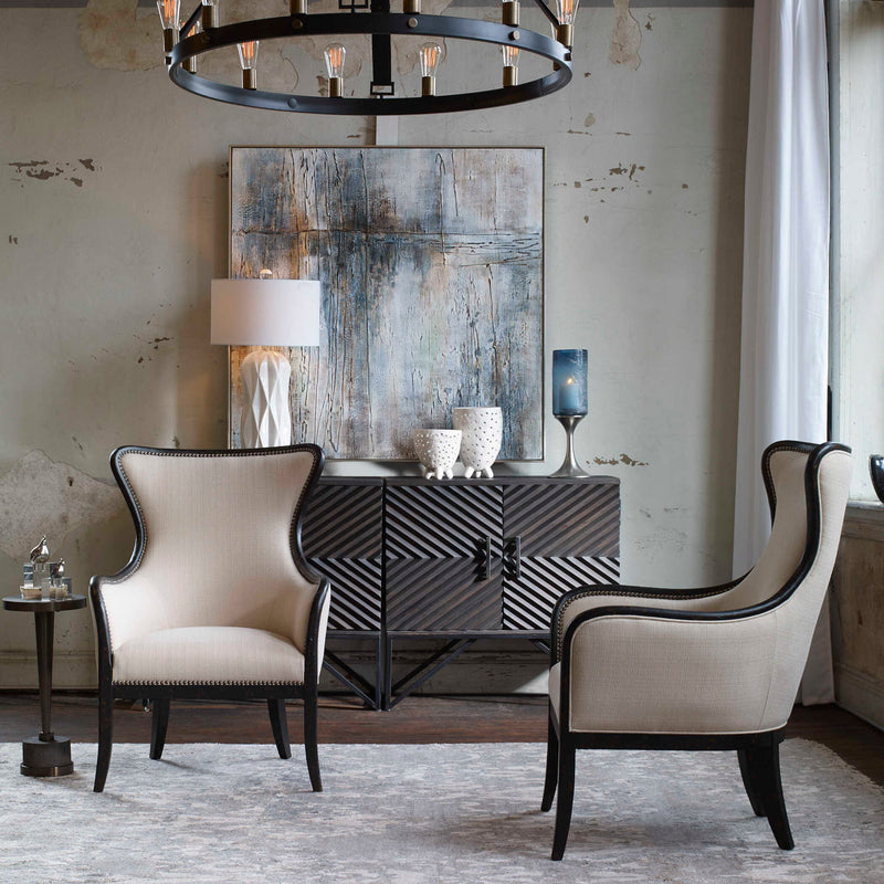 Uttermost Sandy wing back armchair in beige and dark brown fabric with plush cushioning and curved wooden legs.