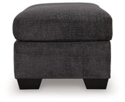 Upholstered Ottoman by Benchcraft® featuring a cushioned top and wooden legs, ideal for living room or lounge decor.