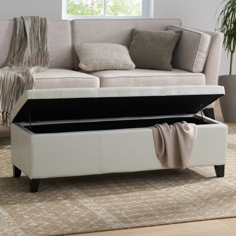 Noble House Glouster contemporary storage ottoman with cushioned top and wooden legs in a modern living room setting