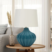 Blue ceramic transitional table lamp with a modern design, featuring a smooth finish and a neutral lampshade.