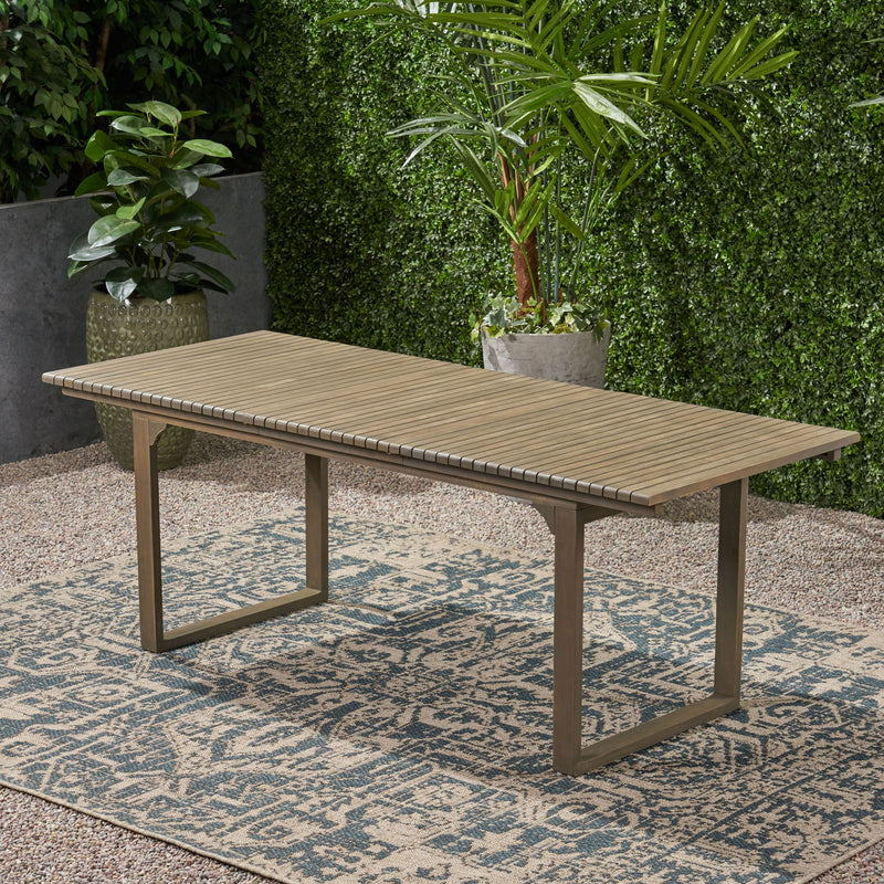 Outdoor expandable acacia wood dining table with U-shaped legs by Noble House, showing the table's surface and sturdy design.
