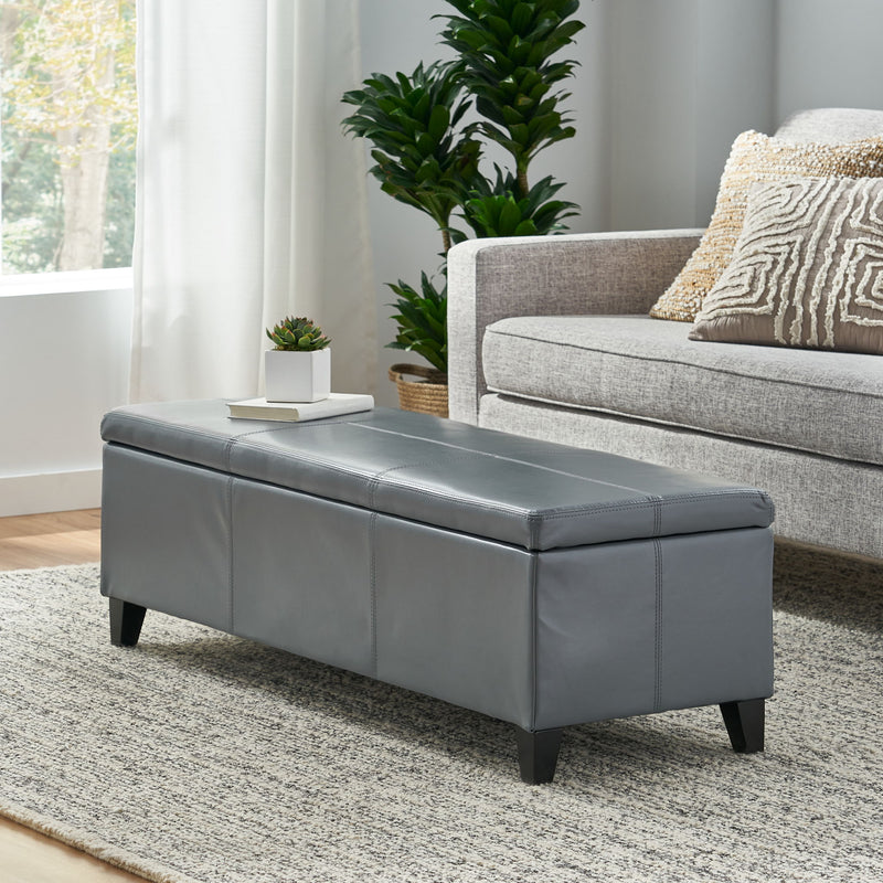 Contemporary Noble House Glouster storage ottoman with cushioned top and wooden legs, ideal for living room storage and seating.