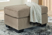 Benchcraft® Olten accent ottoman with a plush fabric top and wooden legs, ideal for living room decor and versatile seating.