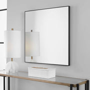 Uttermost Alexo square wall mirror with a sleek, modern frame hanging on a wall, showcasing contemporary home decor.