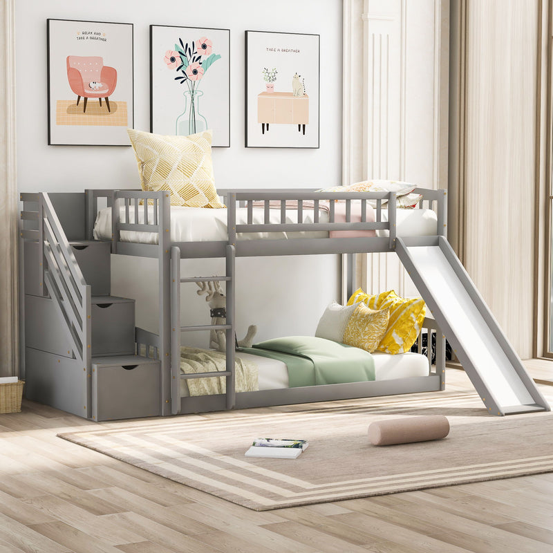 Gray DreamHaus twin over twin bunk bed with stairway, two drawers, and slide, featuring a sturdy wooden design and safety railings.