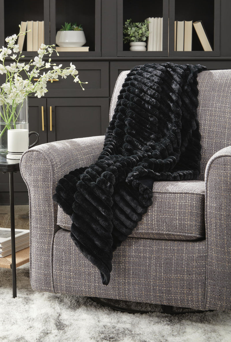 Soft beige Alsonwell throw blanket by Signature Design by Ashley®, draped over a cozy armchair.