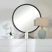 Black round accent mirror by Uttermost with a sleek frame, suitable for modern or contemporary home decor.
