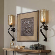 Uttermost Joselyn bronze candle wall sconce with curved design and metal finish, mounted on a wall.