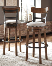 Signature Design by Ashley Valebeck tall upholstered swivel barstool with wooden legs and cushioned seat at bar height.
