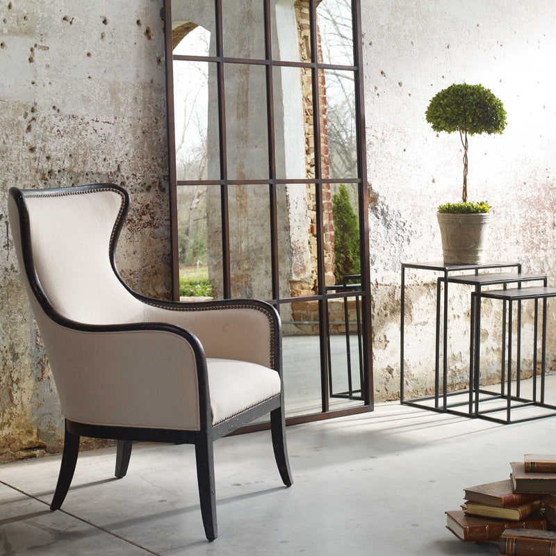 Uttermost Sandy wing back armchair in beige and dark brown fabric with wooden legs and plush cushioning.