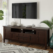 Handcrafted Warm Shaker TV media stand by Simpli-Home with open shelves and storage compartments, made of warm-toned wood.