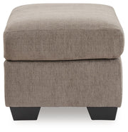 Upholstered Ottoman from Benchcraft® Loreo collection, featuring plush fabric and sturdy wooden legs, perfect for living room use.