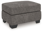 Benchcraft® Olten accent ottoman with a soft fabric surface and wooden legs, used as a versatile indoor footstool or side table.