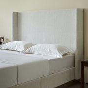 House & Home Furniture Hosford minimalist upholstered wingback bed with wood base platform in a modern bedroom setting.