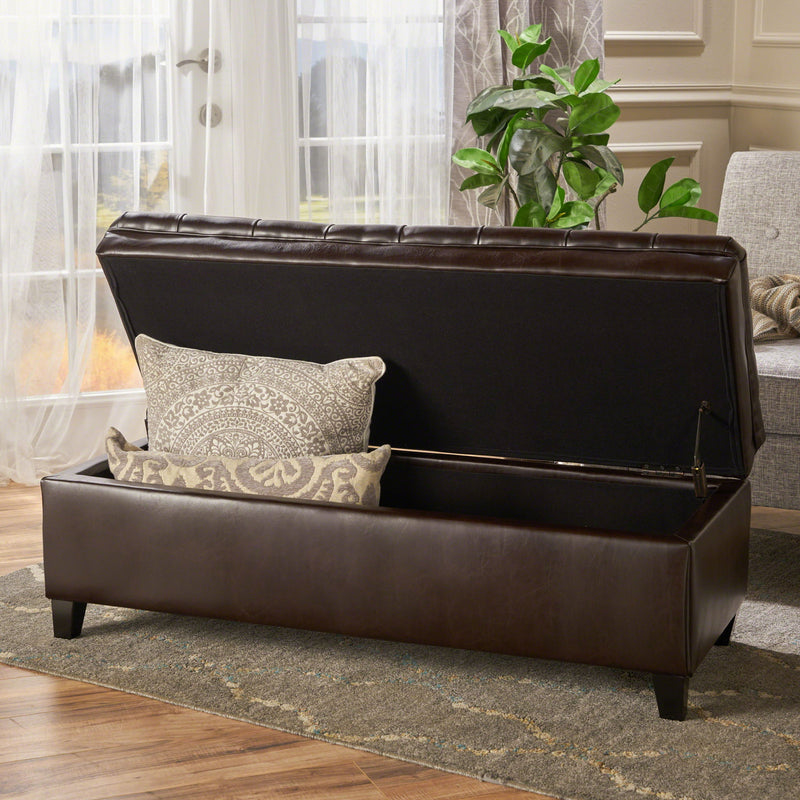 Noble House Juliana storage ottoman with birch wood legs, upholstered in soft fabric, serving as a stylish and functional storage piece.