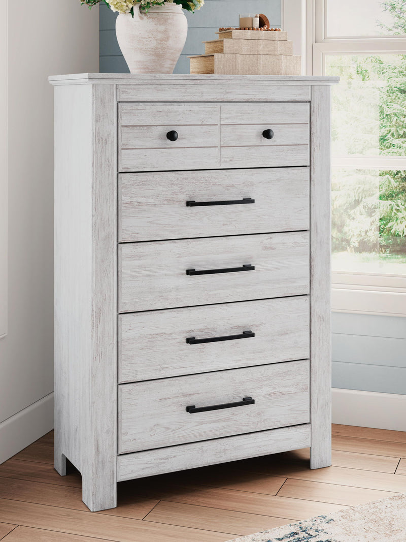 Signature Design by Ashley Makidern five-drawer accent chest with wood finish and modern hardware, standing on four sturdy legs.