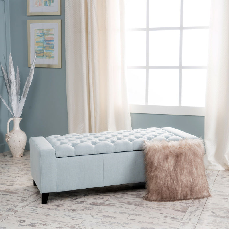 Noble House Guernsey storage ottoman with tufted top, beige fabric and wooden legs, versatile for living room storage.