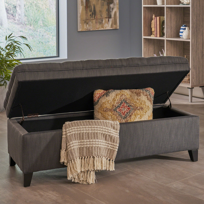 Noble House Juliana storage ottoman with birch wood legs, upholstered in neutral fabric, showing its cushioned top and sturdy base.
