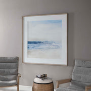 Framed print titled "Surf And Sand" by Uttermost featuring a blue coastal beach scene with waves and sand.
