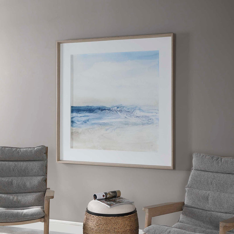 Framed print titled "Surf And Sand" by Uttermost featuring a blue coastal beach scene with waves and sand.