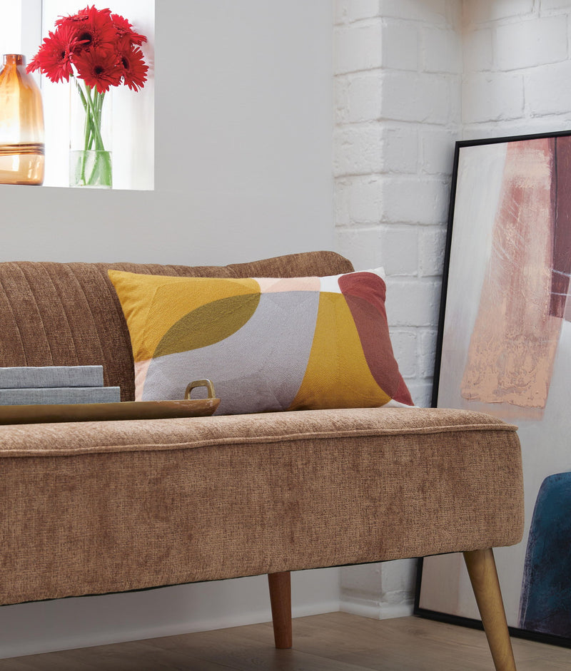 Signature Design by Ashley Varness throw pillow with a textured fabric and decorative pattern on a cozy sofa.