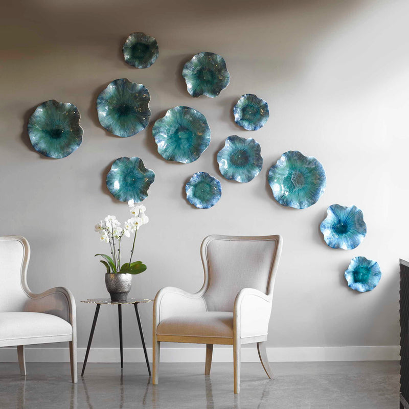 Set of three blue ceramic flower wall decor pieces by Uttermost, featuring detailed flower designs for elegant home decoration.