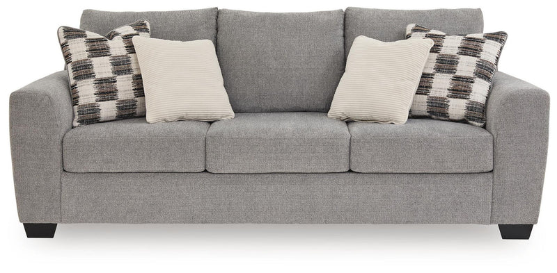 Benchcraft stationary sofa with plush cushions and modern design, featuring neutral fabric upholstery and wide armrests.