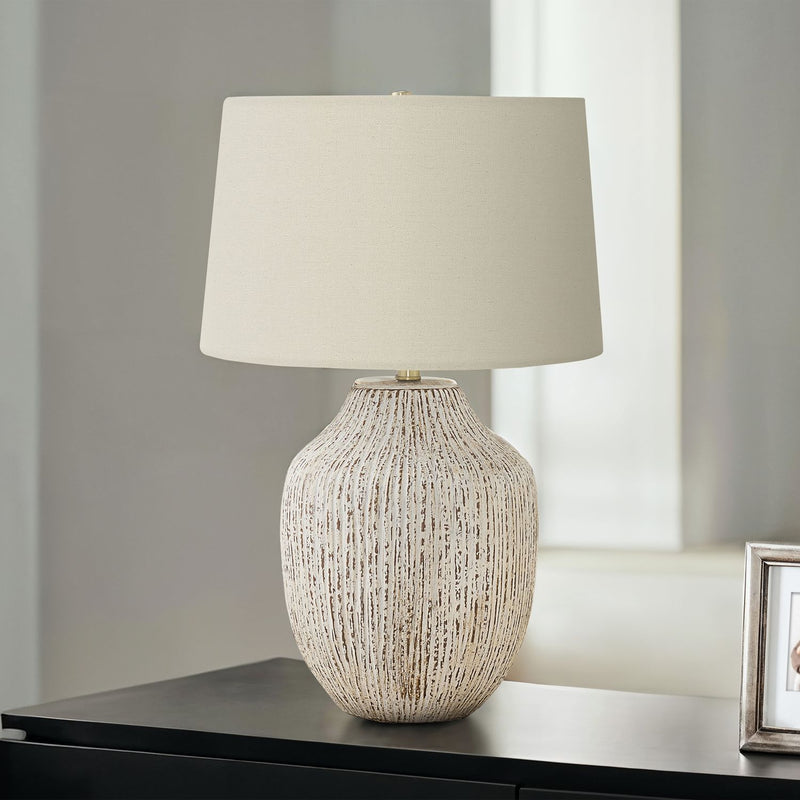 Cream ceramic table lamp with transitional design, featuring a smooth rounded base and a fabric shade for soft ambient lighting.