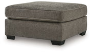 Benchcraft® Olten accent ottoman with a cushioned top and wooden legs, perfect for added style and comfort in living spaces.