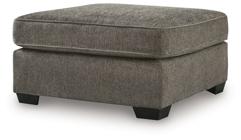 Benchcraft® Olten accent ottoman with a cushioned top and wooden legs, perfect for added style and comfort in living spaces.