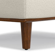 Simpli-Home Morrison handcrafted upholstered ottoman with plush fabric and wooden legs, showcasing a versatile living room accent piece.