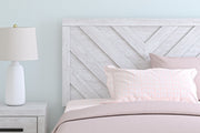 Signature Design by Ashley Cayboni Panel Bed with a modern wooden frame and headboard, shown in a cozy bedroom setting.