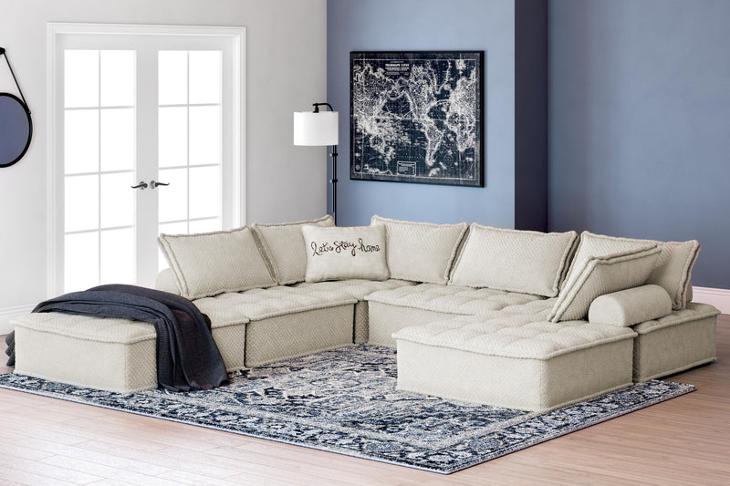 Signature Design by Ashley stationary sectional sofa with plush cushions and neutral fabric in a modern living room setting.
