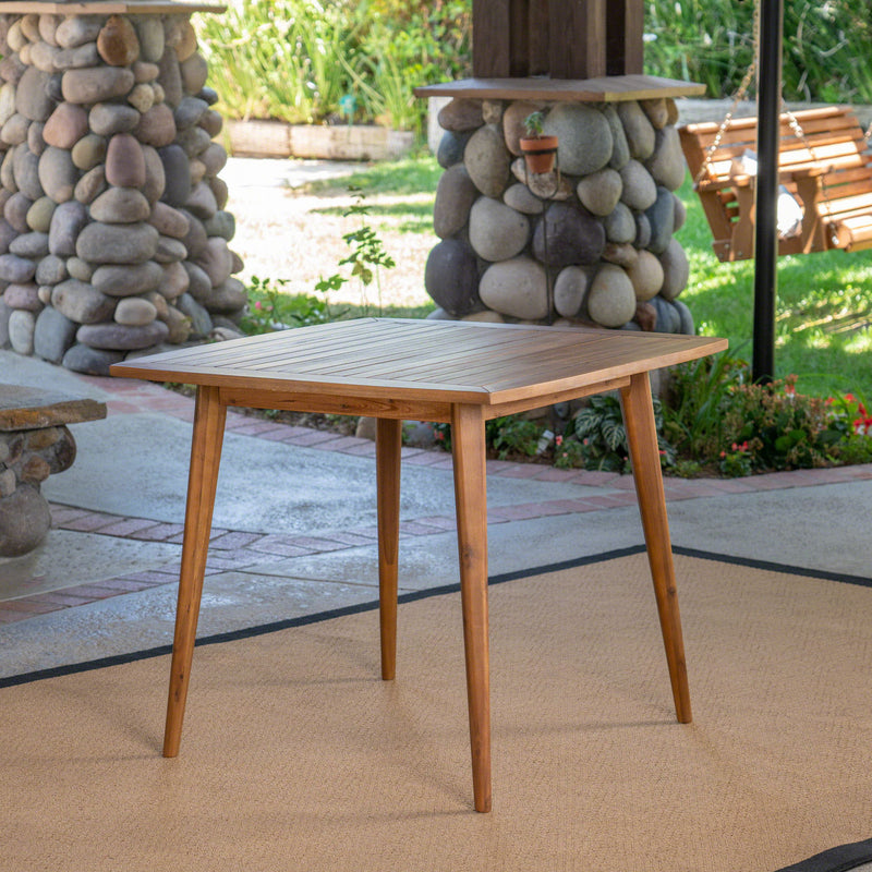 Modern indoor square dining table with acacia wood surface and toothpick leg design by Noble House