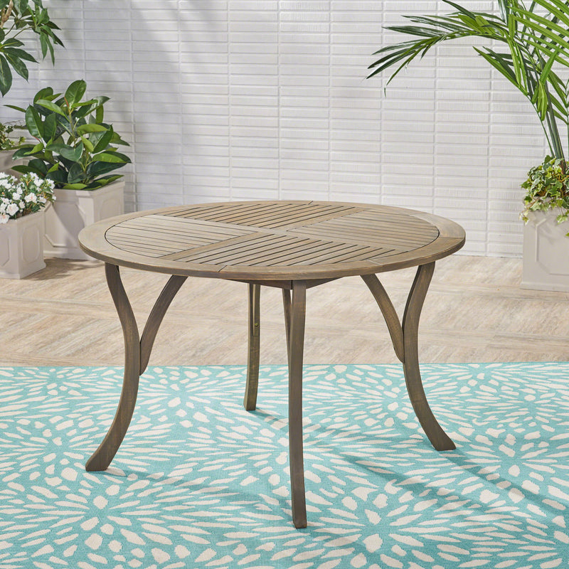 Noble House Hermosa outdoor acacia wood dining table with a circular design, perfect for patio or garden seating.