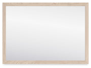 Signature Design by Ashley Cadmori bedroom mirror with a sleek rectangular frame, reflecting a modern bedroom decor.