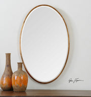 Herleva gold oval wall mirror by Uttermost with a sleek, reflective surface and a stylish gold frame for elegant home decor.