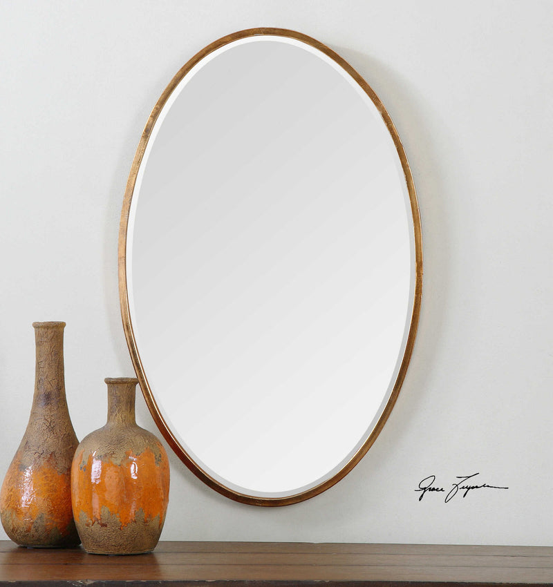 Herleva gold oval wall mirror by Uttermost with a sleek, reflective surface and a stylish gold frame for elegant home decor.