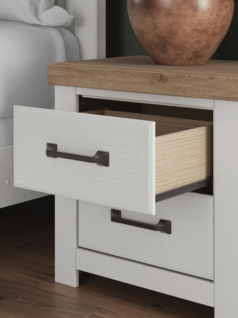 Benchcraft white and brown two-drawer nightstand with charging station, modern design, featuring sleek drawers and a sturdy build.