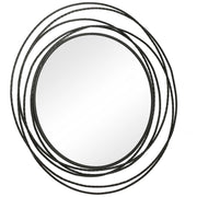 Uttermost Whirlwind round wall mirror with a decorative metal frame, hanging on a wall in a modern interior setting.