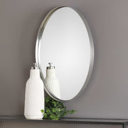 Uttermost Pursley oval wall mirror with brushed nickel finish, showcasing a sleek, modern design mounted on a wall.